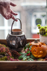 pumpkin and candles for the autumn holiday of Halloween, on a wooden tray at the window