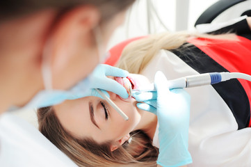 Dentist whitens teeth to patient - attractive girl