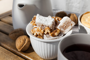 Closeup of Organic Lukum in a White Cup with Tea and Walnuts placed on Wooden Table
