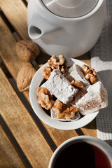 Organic Lukum in a White Cup with Tea and Walnuts placed on Wooden Table, Top View