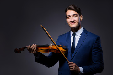 Young man playing violin in dark room
