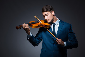 Young man playing violin in dark room