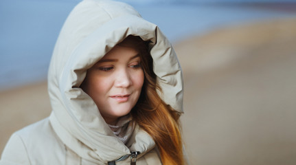 Outdoor portrait of sad young woman girl in hood. Winter time