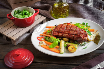 grilled steak on plate with vegetables on wooden background