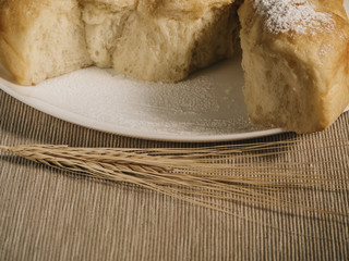 Homemade pastries on a white dish and wheat spikes in vintage processing