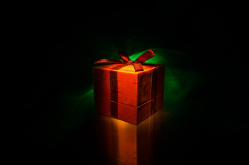 red gift box with red bow on dark toned background