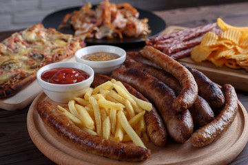 Appetizing beer snacks close up. Grilled sausages with french fries and sauces, Oktoberfest food, pub concept