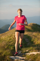 Woman runs on a top of the mountains with mountain range in background