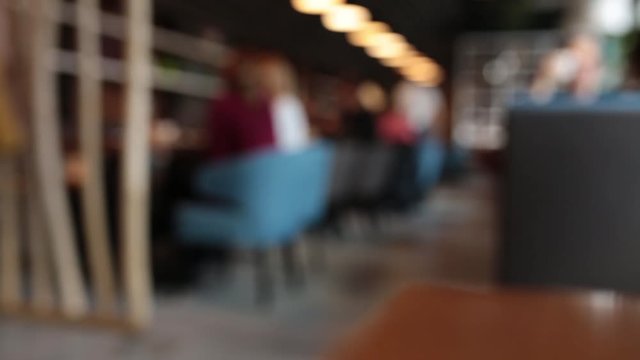 Defocused background - a group of people is sitting in a modern restaurant.