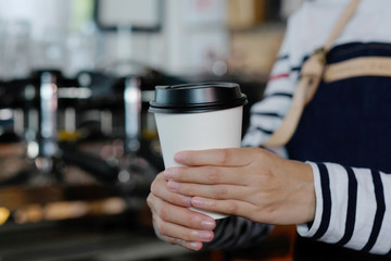 Barista hands holding a take away coffee cup with at cafe counter background, small business owner, food and drink industry concept