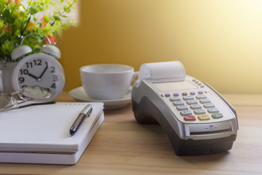 Credit Card Terminal or EDC on cashier wooden table in the store with calculator, clock,credit cards and laptop on wooden / technology and market concept