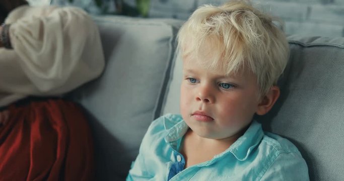close up child is sitting on the couch looking sideways boy thought blond hair looked serious at home relaxing little portrait young Slow Motion Shot Shot on RED EPIC camera