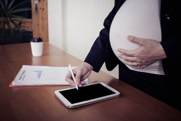 Pregnant woman working on tablet.