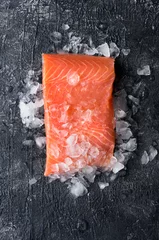 Fotobehang Fresh salmon (trout) fillet on dark background with ice. Top view.  © masterq