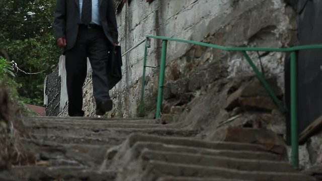 The man working in a suit is descending from concrete stairs