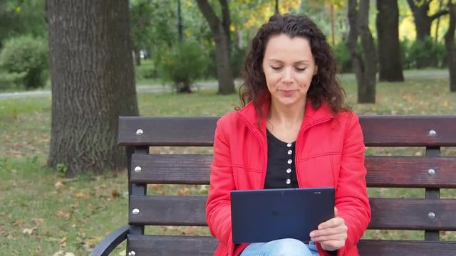 Girl with a gadget in the autumn park. happy girl with a pannier on the nature.