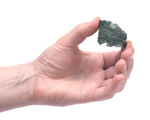 Woman's hand holding Moldavite (form of tektite found along the banks of the river Moldau in Czech...
