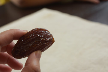 close up fingers holding dried date fruit on table