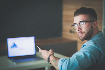 Young man using phone and works on the laptop.