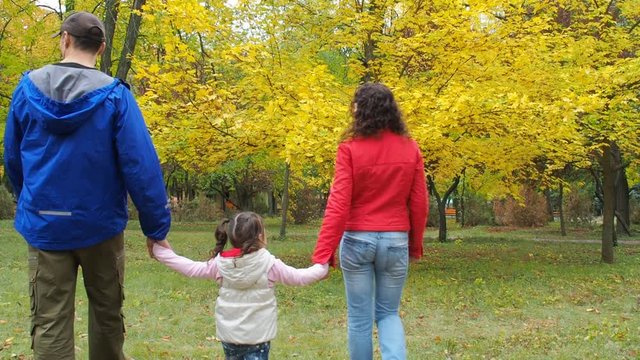 Family in the autumn park. Parents and daughter are walking in the park.