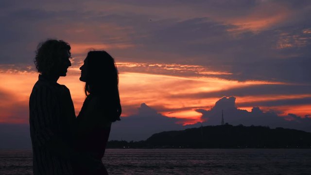 Cople kissing silhouettes on beach in front of ocean sunset and island. Shot with Sony a7s and Atomos Ninja Flame in Gili Meno, Indonesia.