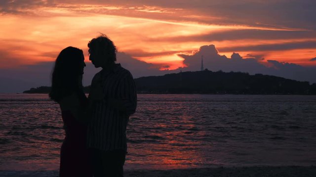 Cople kissing silhouettes on beach in front of ocean sunset and island. Shot with Sony a7s and Atomos Ninja Flame in Gili Meno, Indonesia.