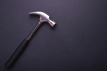 New silver hammer on black granite board background. Composition with free space for text or design.