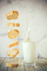 Bread and milk. Flying baguette and milk splash in a glass