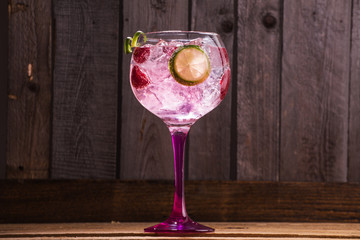 Pink tonic gin with raspberries, wooden background