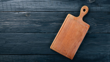 Kitchen wooden board. On a wooden background. Top view. Free space for your text.