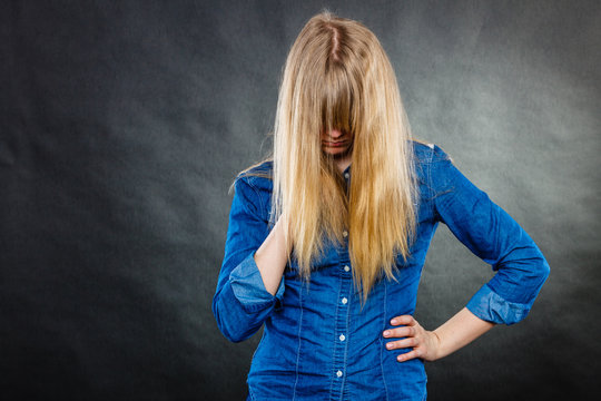 Depressed blonde woman covering face.