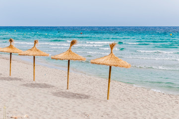 Straw umbrellas on sand beach.