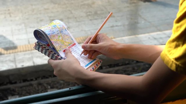 Young boy on a train writing notes in map planning for travel. Backpacker planning on traveler map with notebook. Asia boy travel by train.