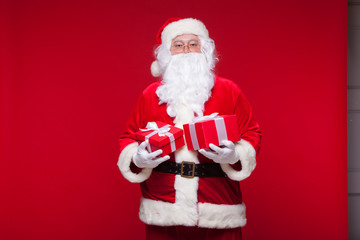 Christmas. Photo Santa Claus giving xmas present and looking at camera, on a red background