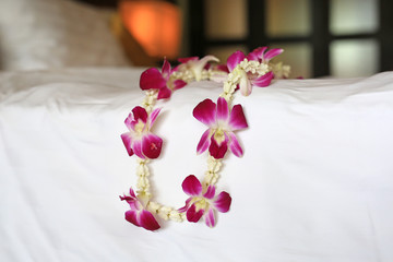Welcome orchids garland place on the bed of luxury hotel in thailand.