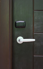 Door handle with access key on wooden door.