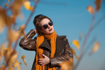 girl on a background of nature sky and yellow leaves in autumn