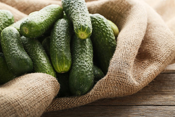 Fresh cucumbers with sackcloth on grey wooden table