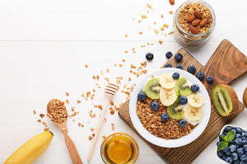 Tasty granola with berries in plate with honey on white wooden table