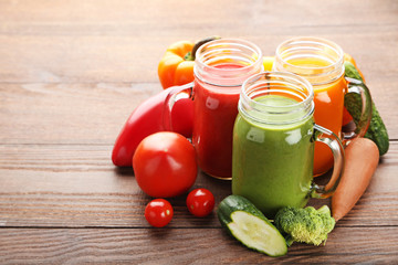 Vegetables smoothie in jars on wooden table