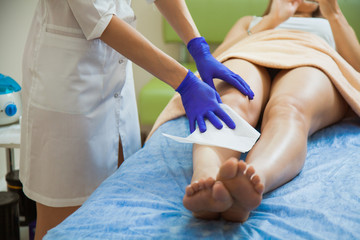 Young woman making sugaring hair removal procedure at beauty salon. Beautician cosmetologist make epilation with liquid sugar paste. talcum powder