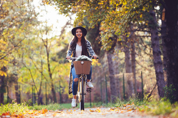 Happy active woman riding bike bicycle in fall autumn park