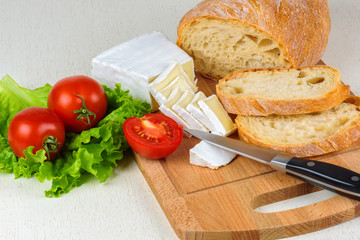 Breakfast from bread, cheese, tomatoes and all-over salad on a wooden table closeup.