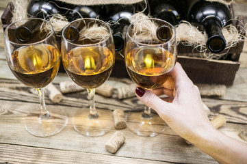 Three glasses of white wine on a wooden background.  Female hand holds a glass with wine. Alcoholic beverages background