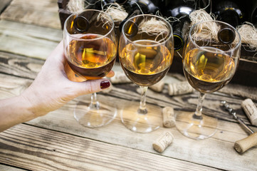 Three glasses of white wine on a wooden background.  Female hand holds a glass with wine. Alcoholic beverages background