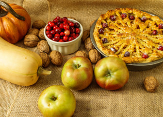 Fall traditional apple pie still life with pumpkin, cranberry and apples.