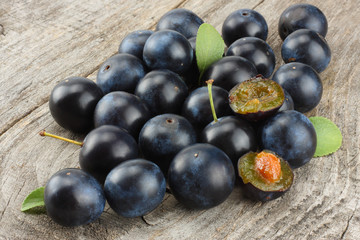 blackthorn berries with green leaf on old wooden table