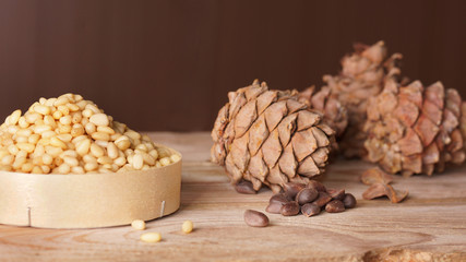 Cedar cones and pine nuts are on a wooden table