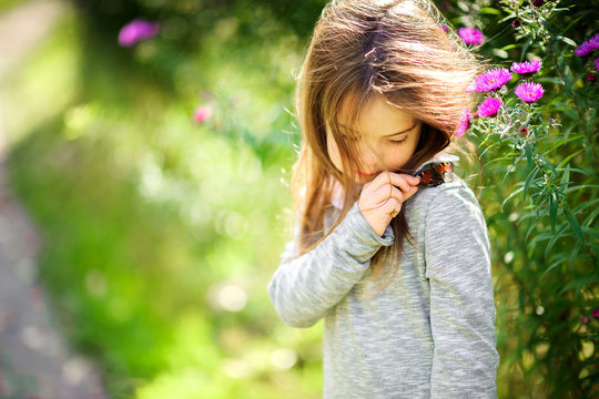 happy little girl is walking in a beautiful park with a butterfly on her shoulder.