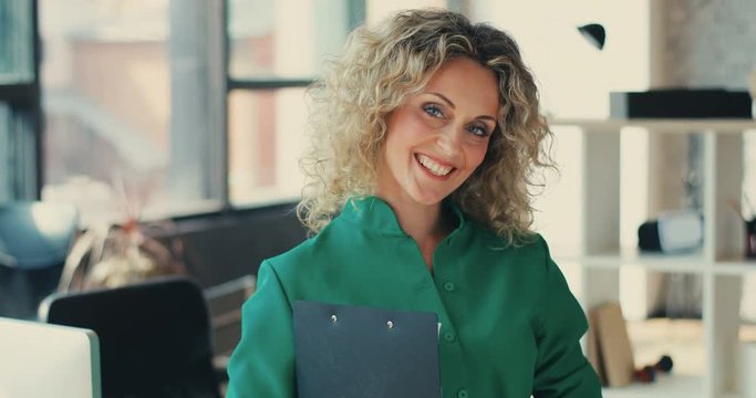 Portrait of successful happy businesswoman with blond curly hair looking at camera at office business manager company success team technology leadership close up Slow Motion Shot